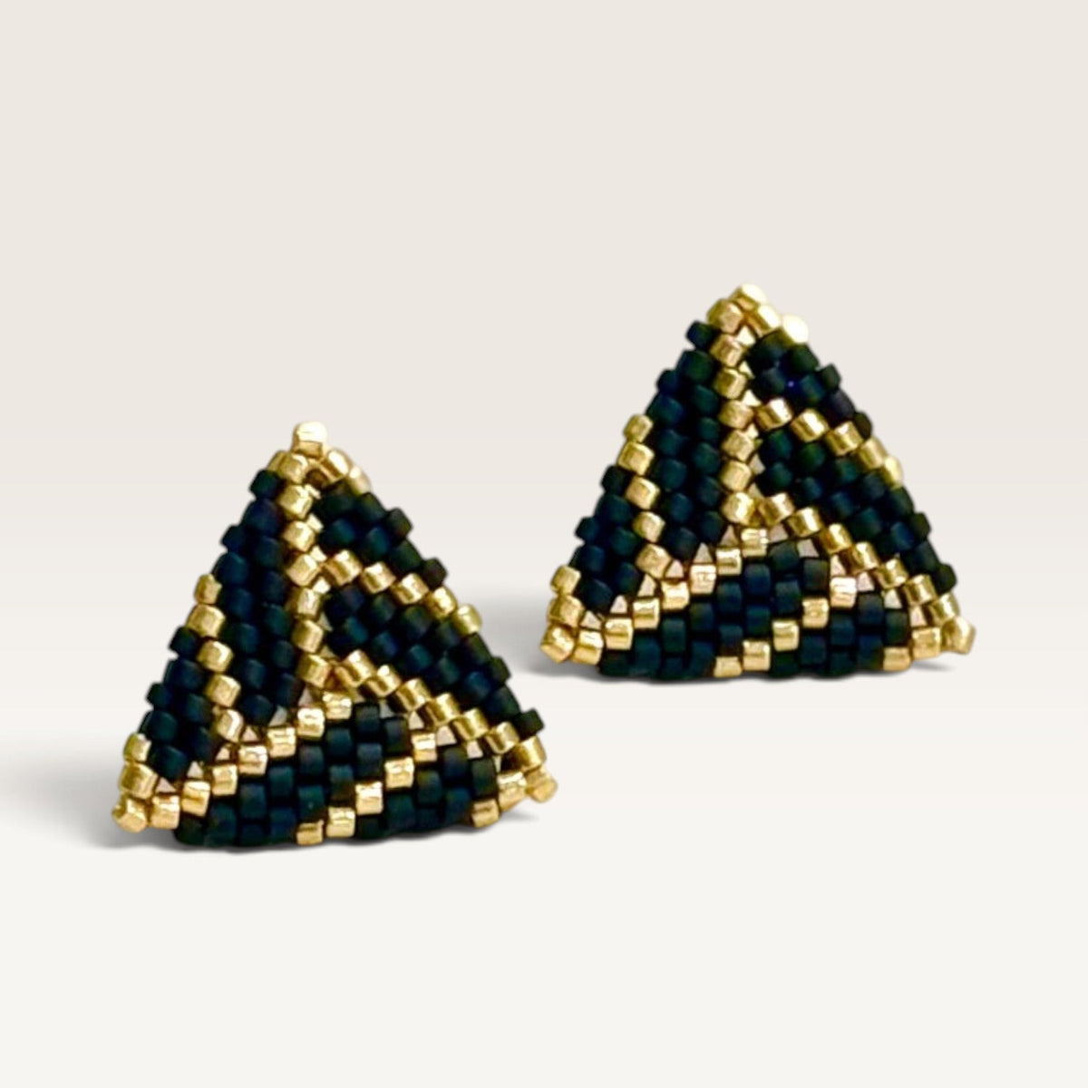Ritelia Sofía triangle earrings handcrafted with black and gold Japanese Miyuki beads in a geometric pattern.